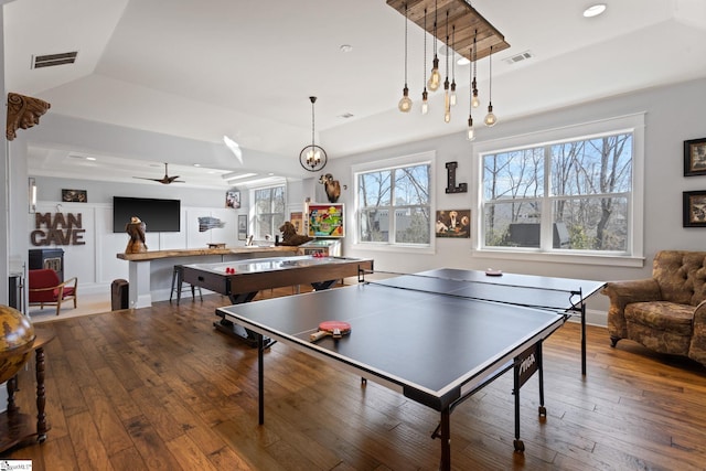 rec room featuring hardwood / wood-style floors, a raised ceiling, and visible vents