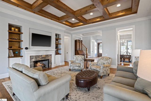 living area featuring a stone fireplace, coffered ceiling, and wood finished floors