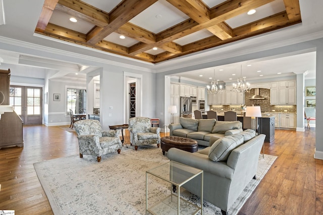 living area featuring light wood finished floors, coffered ceiling, an inviting chandelier, crown molding, and beam ceiling