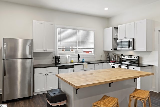 kitchen featuring appliances with stainless steel finishes, a breakfast bar, a sink, open shelves, and wooden counters