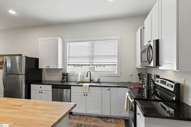 kitchen featuring wood counters, stainless steel appliances, white cabinetry, a sink, and recessed lighting