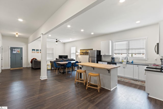 kitchen with stainless steel appliances, dark wood-style flooring, wood counters, a kitchen breakfast bar, and open floor plan