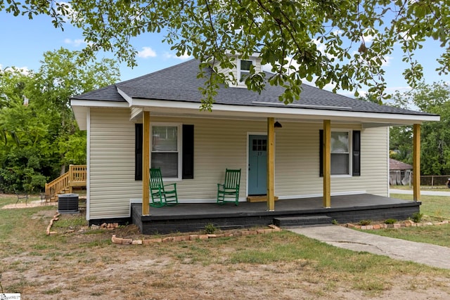 bungalow-style house featuring covered porch, roof with shingles, and central AC unit