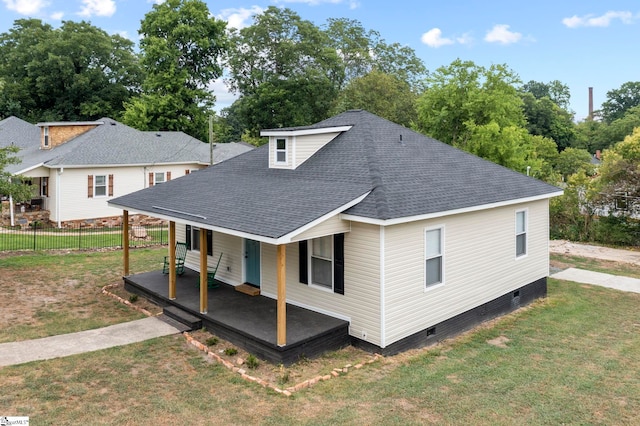 rear view of property featuring roof with shingles, crawl space, covered porch, fence, and a yard