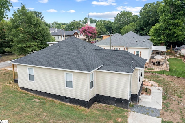 back of house featuring a shingled roof, crawl space, fence, and a lawn