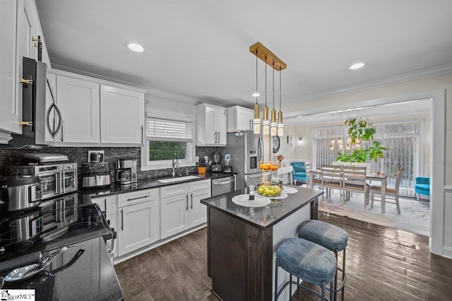 kitchen with decorative backsplash, ornamental molding, dark wood-type flooring, stainless steel appliances, and a sink