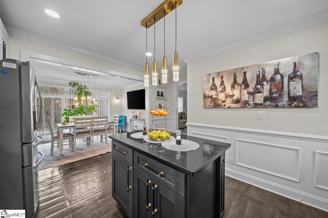 kitchen with dark wood finished floors, ornamental molding, freestanding refrigerator, wainscoting, and dark cabinetry