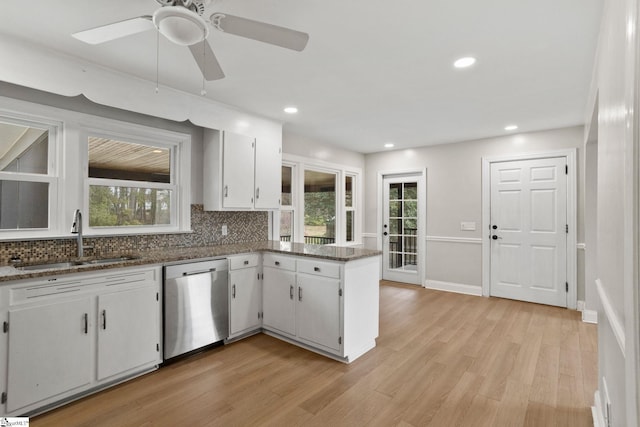 kitchen featuring light wood finished floors, plenty of natural light, dishwasher, white cabinetry, and a sink