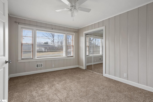 unfurnished bedroom with ornamental molding, multiple windows, carpet, and visible vents