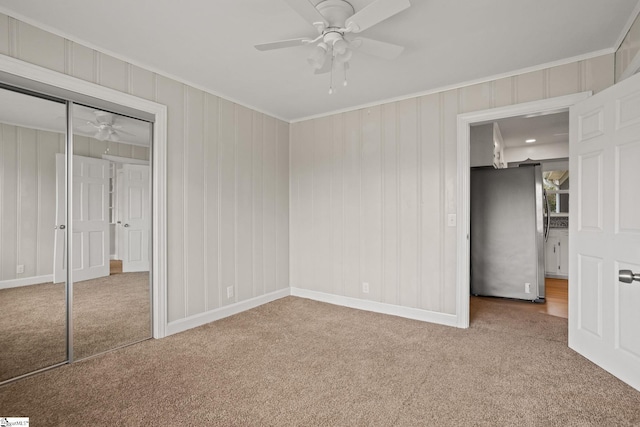 unfurnished bedroom featuring carpet floors, freestanding refrigerator, a closet, and crown molding