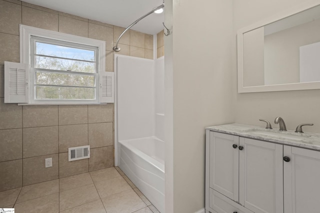 full bath with bathing tub / shower combination, tile walls, visible vents, vanity, and tile patterned floors