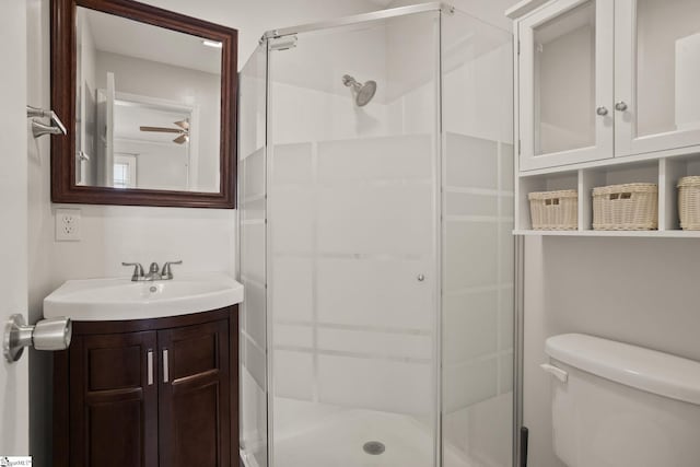 full bathroom with ceiling fan, vanity, a shower stall, and toilet