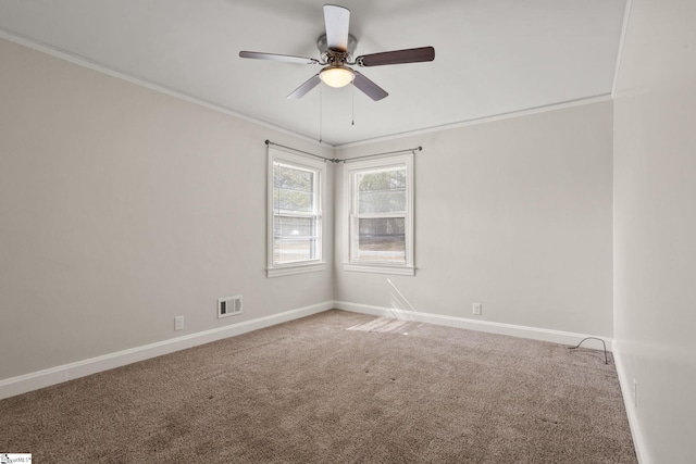 carpeted empty room featuring a ceiling fan, visible vents, baseboards, and crown molding