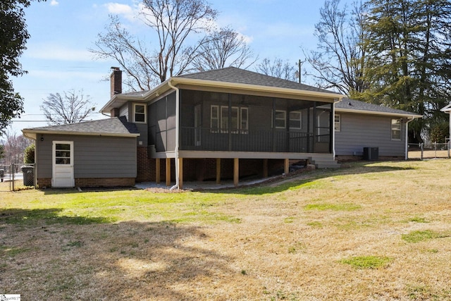 rear view of property with a sunroom, a chimney, fence, a yard, and central AC