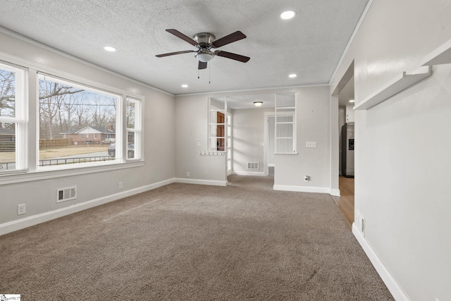 unfurnished living room featuring visible vents, carpet flooring, a textured ceiling, and ornamental molding