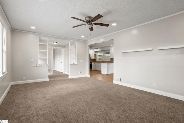 unfurnished living room with carpet, crown molding, visible vents, ceiling fan, and a textured ceiling