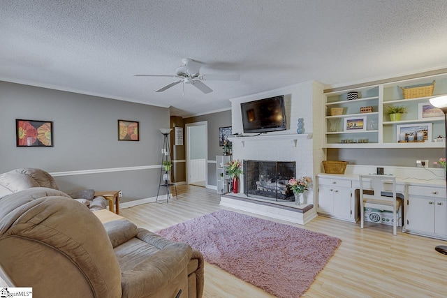 living room with a brick fireplace, light wood-style flooring, ornamental molding, and a textured ceiling