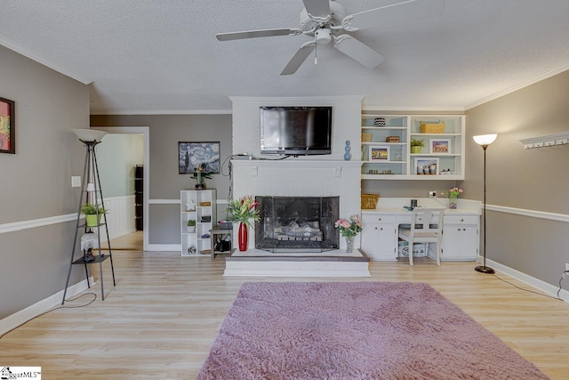 unfurnished living room with light wood-type flooring, a fireplace, ornamental molding, and a textured ceiling