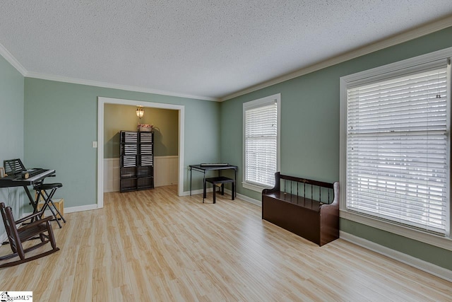 living area with ornamental molding, a textured ceiling, baseboards, and wood finished floors