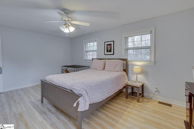 bedroom featuring ceiling fan, wood finished floors, visible vents, and baseboards