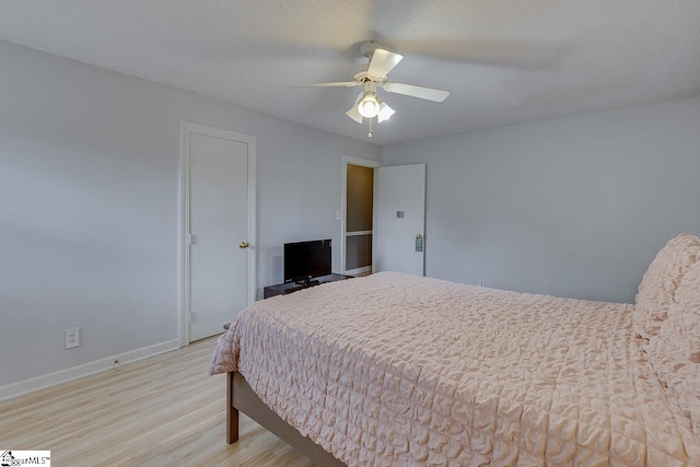 bedroom featuring baseboards, ceiling fan, a textured ceiling, and light wood finished floors