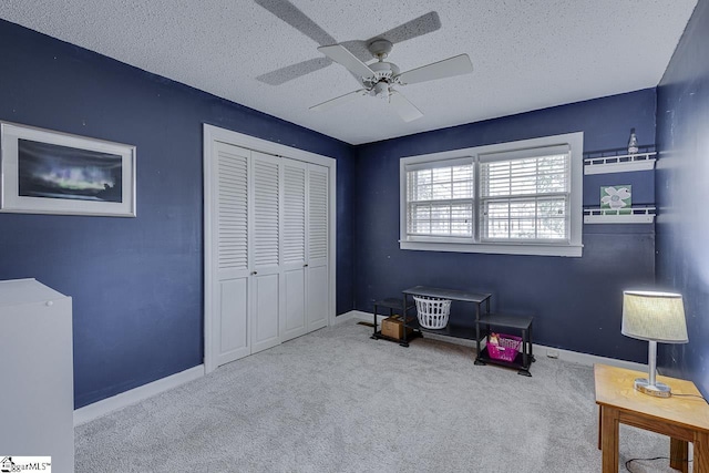 living area with carpet, baseboards, ceiling fan, and a textured ceiling