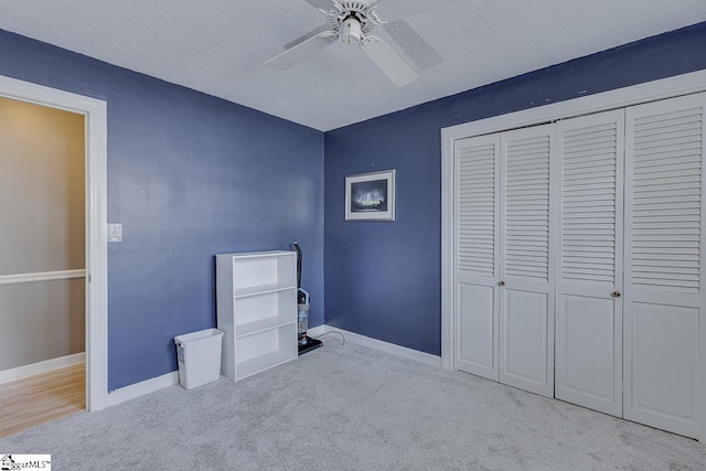 unfurnished bedroom with carpet, a closet, ceiling fan, a textured ceiling, and baseboards