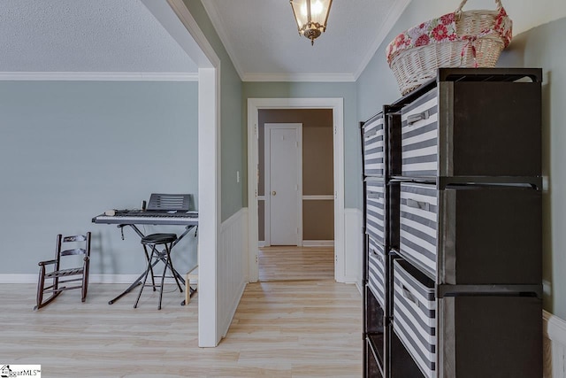 kitchen with light wood finished floors, ornamental molding, and a textured ceiling