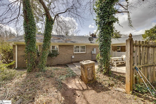 back of property with a patio area, a chimney, fence, and brick siding