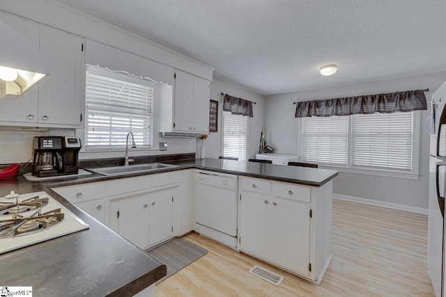 kitchen with dark countertops, white appliances, a sink, and exhaust hood