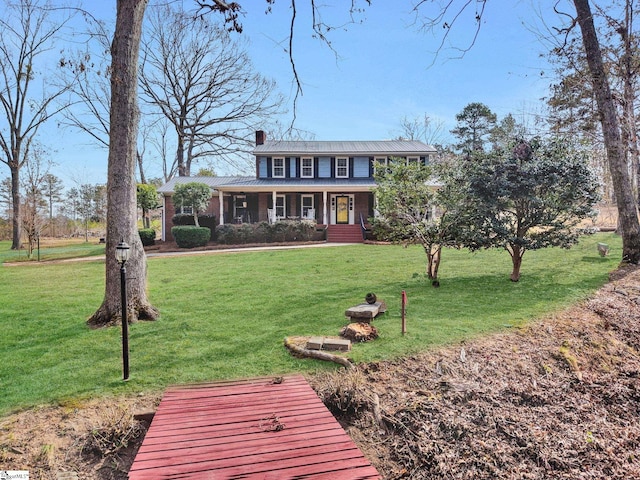 view of front of property featuring covered porch, a chimney, and a front yard