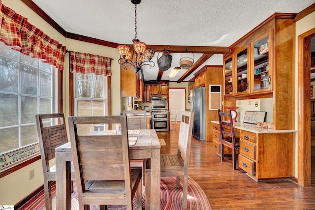 dining area with an inviting chandelier, beam ceiling, dark wood finished floors, and a textured ceiling