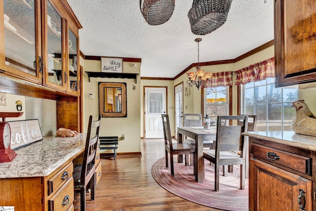 dining area featuring a chandelier, a textured ceiling, wood finished floors, baseboards, and ornamental molding