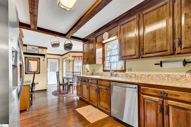 kitchen featuring dark wood-type flooring, a sink, stainless steel appliances, a textured ceiling, and beam ceiling