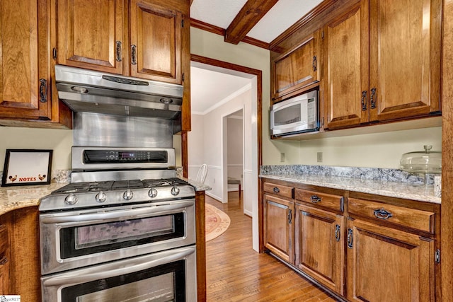 kitchen with brown cabinets, white microwave, range with two ovens, and exhaust hood
