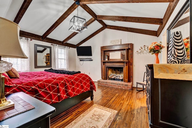 bedroom with a brick fireplace, vaulted ceiling with beams, hardwood / wood-style floors, and an inviting chandelier
