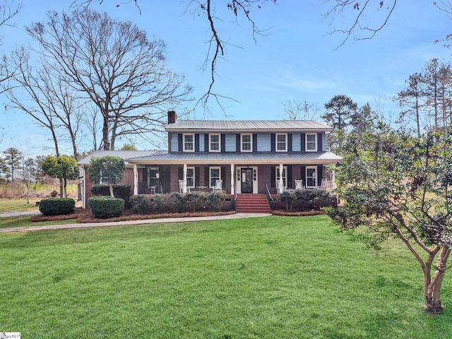 view of front of house with covered porch, brick siding, a chimney, and a front lawn