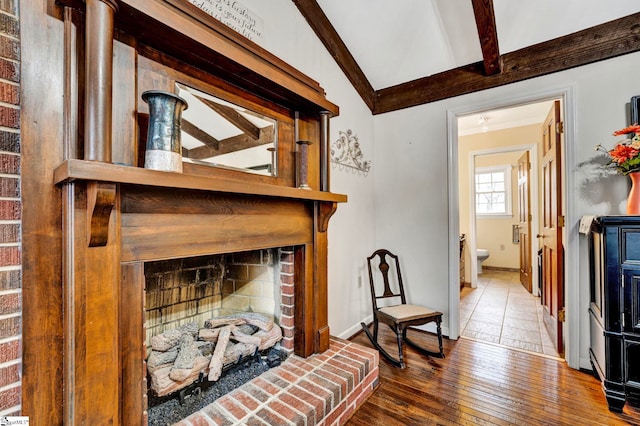living room with vaulted ceiling with beams, a fireplace, hardwood / wood-style floors, ornamental molding, and baseboards