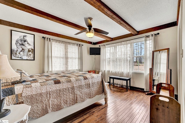 bedroom featuring hardwood / wood-style floors, ceiling fan, a textured ceiling, beamed ceiling, and baseboards