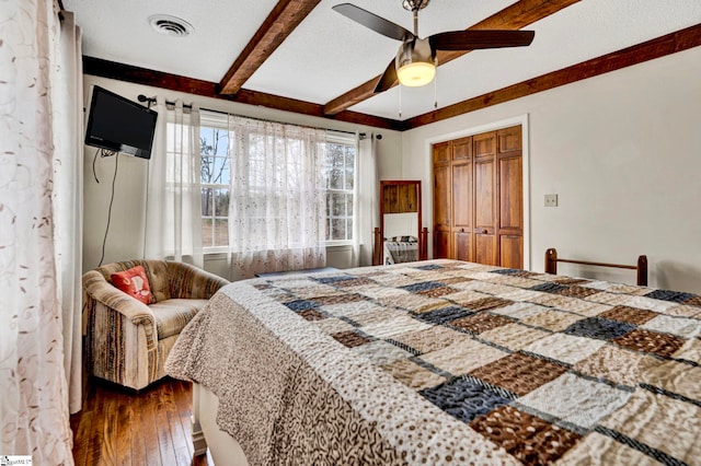 bedroom featuring ceiling fan, a textured ceiling, dark wood-style flooring, visible vents, and beam ceiling
