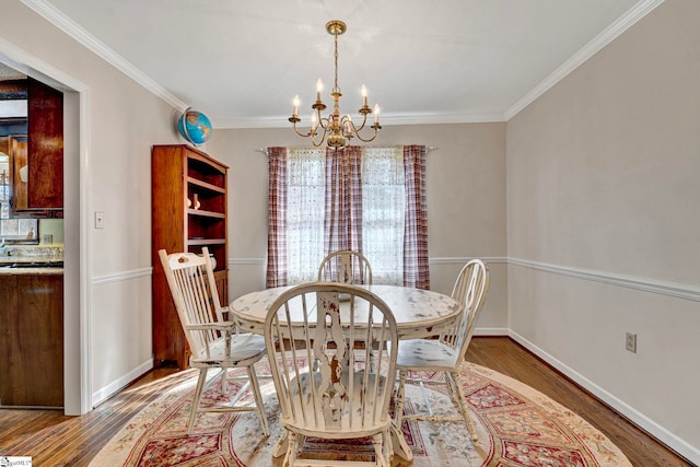 dining space with a chandelier, ornamental molding, baseboards, and wood finished floors