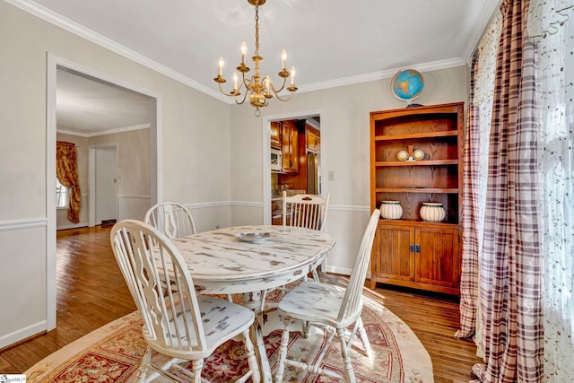 dining space with light wood-style floors, a notable chandelier, crown molding, and baseboards