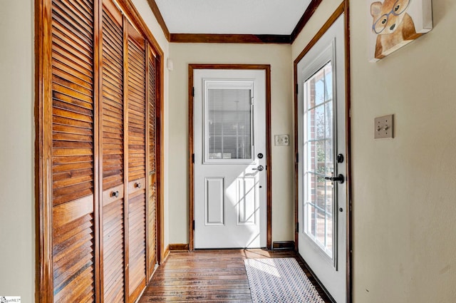 doorway featuring ornamental molding, a wealth of natural light, dark wood-style flooring, and baseboards