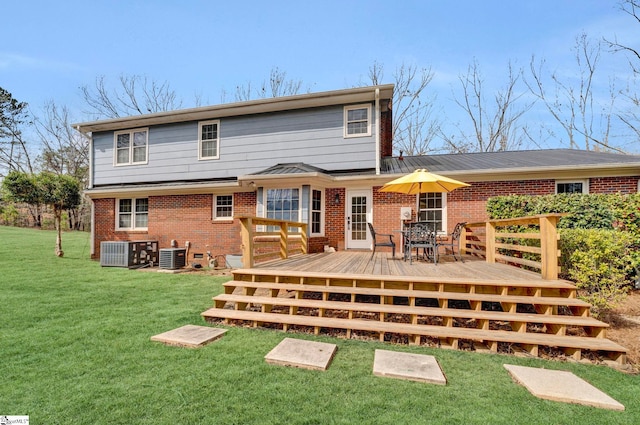 rear view of property featuring a wooden deck, cooling unit, a lawn, and brick siding
