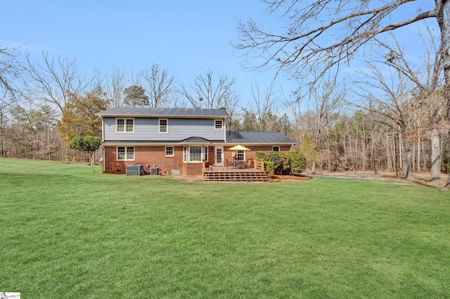 back of house featuring central AC, a yard, a wooden deck, and brick siding