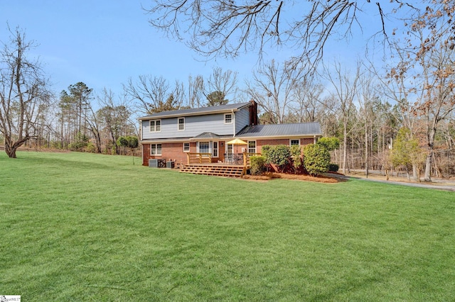 rear view of house with a yard, a deck, and brick siding