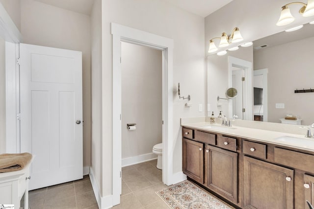 bathroom with double vanity, a sink, toilet, and tile patterned floors