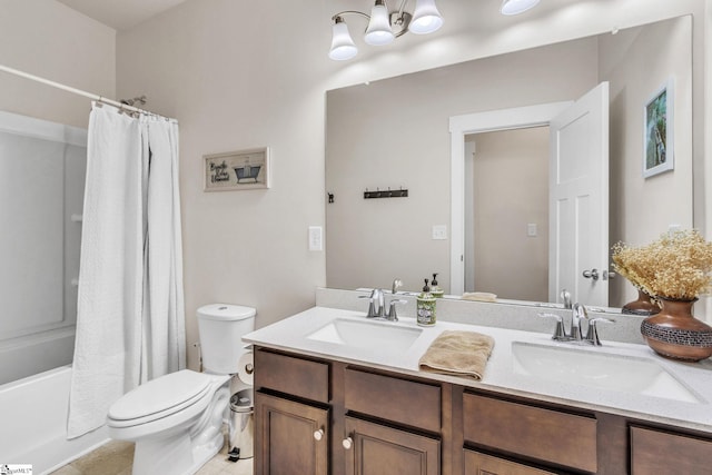 full bath with double vanity, a sink, toilet, and an inviting chandelier