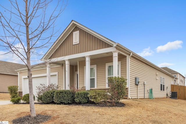 view of front of house with a garage, board and batten siding, cooling unit, and fence