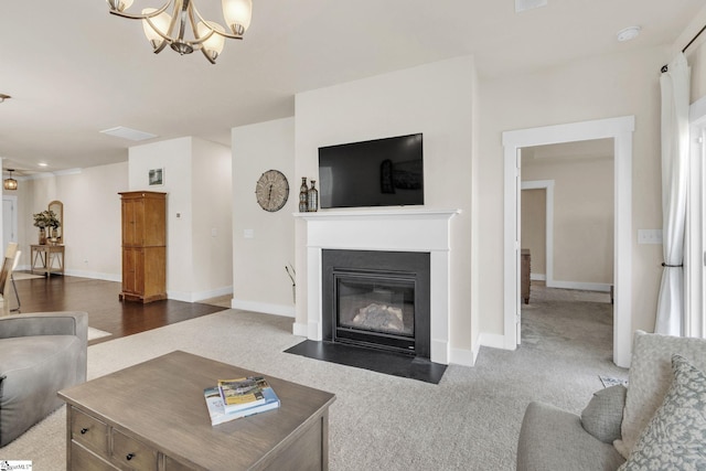 living room with a fireplace with flush hearth, dark colored carpet, a chandelier, and baseboards